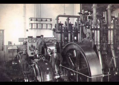 Personal de la Compañía del Sud Argentino (SUDAM) en el año 1917. Empleados posan junto a grupo de generadores de corriente continua en el edificio de la esquina de San Martín y Almafuerte.