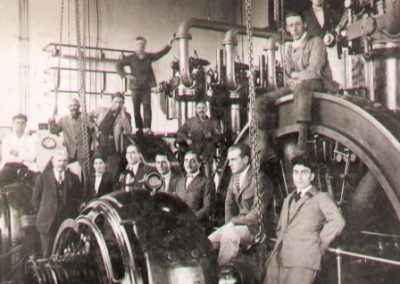 Personal de la Compañía del Sud Argentino (SUDAM) en el año 1917. Empleados posan junto a grupo de generadores de corriente continua en el edificio de la esquina de San Martín y Almafuerte.